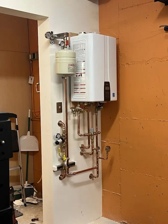 Plumbing technician inspecting water heater connections in Longswamp